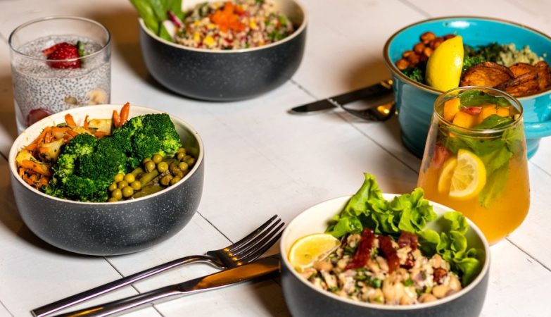 A vibrant assortment of healthy bowls and drinks showcasing fresh ingredients like broccoli and citrus.