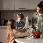 A happy family of three enjoying quality time unpacking vegetables in a modern kitchen.
