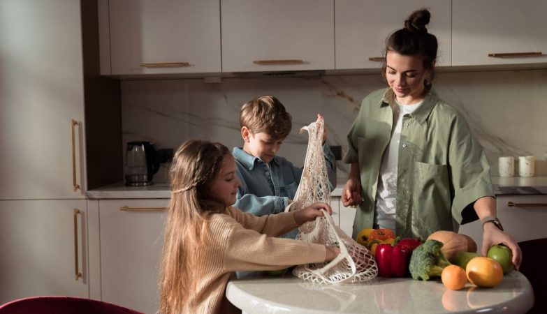 A happy family of three enjoying quality time unpacking vegetables in a modern kitchen.