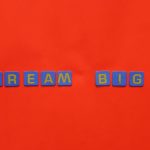 Blue tiles forming the 'Dream Big' quote against a striking red background.