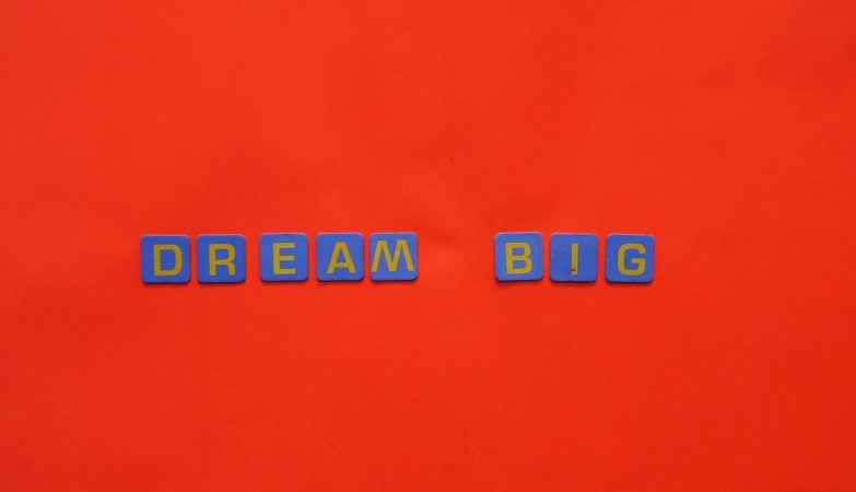 Blue tiles forming the 'Dream Big' quote against a striking red background.
